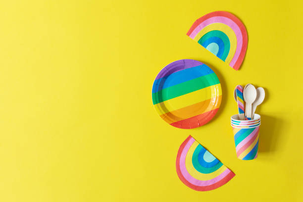istock Rainbow colored disposable eco tableware on yellow color background top view. Birthday party accessories,picnic utensil concept. 1202816463