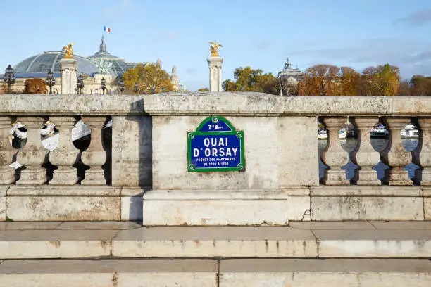 Quai Orsay typical street sign and stone balustrade with Grand Palais view in Paris, France