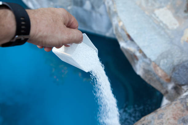 Swimming Pool Shock Chlorination 1/5 Pouring liquid chlorine into swimming pool as part of a regular maintenance. chlorine stock pictures, royalty-free photos & images