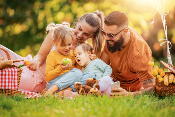 Smiling family picnicking in summer park stock photo
