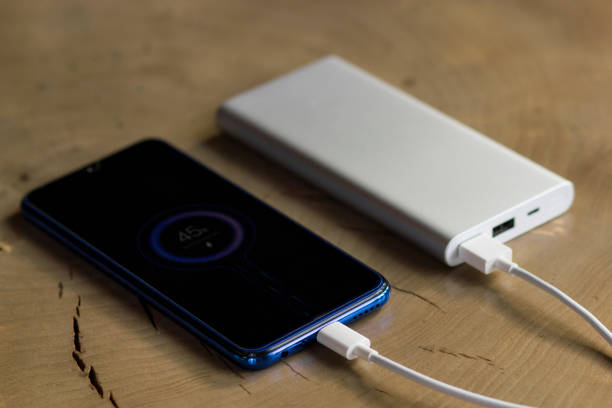 istock Smartphone charging with power bank on wooden table. Charge share 1202827866