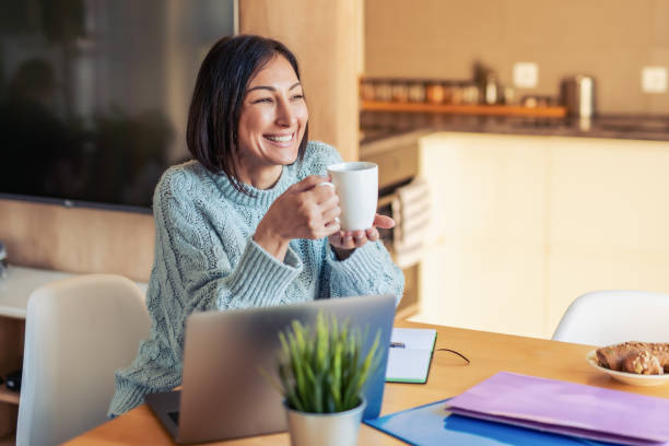 Business woman working on her laptop and drinking coffee stock photo