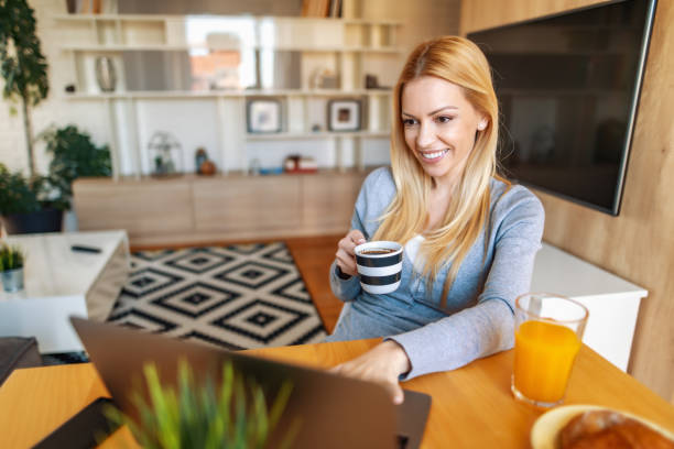 Smiling woman working on laptop at home stock photo