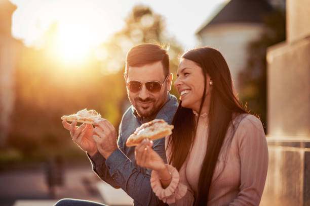 Smiling couple enjoying in pizza outdoors stock photo