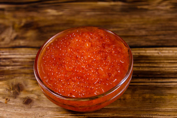 tigela de vidro com caviar vermelho em uma mesa de madeira - heap caviar animal egg fish roe - fotografias e filmes do acervo