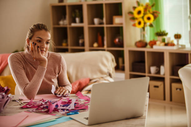 istock Young woman watching a tutorial on how to craft paper flowers 1202845514