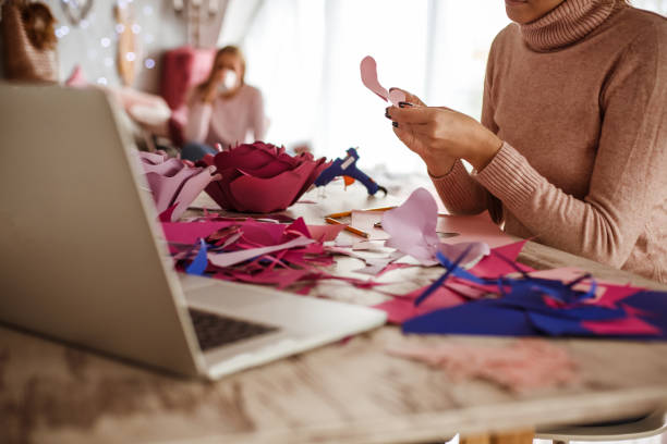istock Unrecognizable young woman making paper flowers while following a video tutorial on her laptop 1202845518