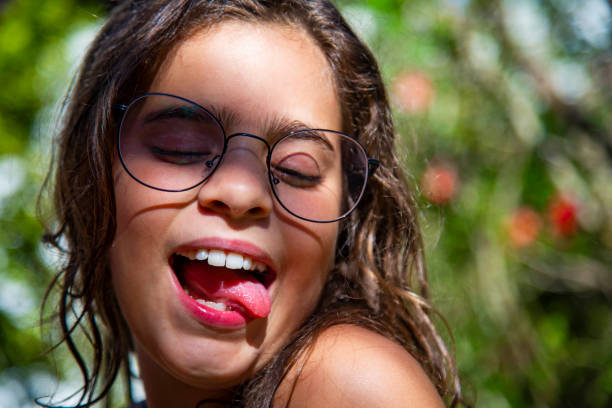 istock Litle girl pulling a face showing the tongue with glasses 1202846830