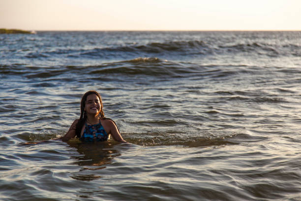 istock Litle girl smiling inside the beach water 1202846995