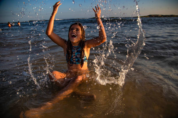 istock Little girl throwing water on the beach 1202846996