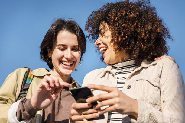 istock two women laughing looking the phone 1202847195