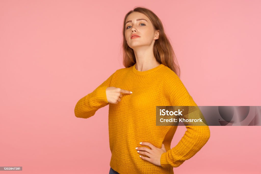 This is me! Portrait of attractive haughty ginger girl in sweater pointing at herself and looking at camera with arrogance This is me! Portrait of attractive haughty ginger girl in sweater pointing at herself and looking at camera with arrogance, proud and confident in success. studio shot isolated on pink background Women Stock Photo