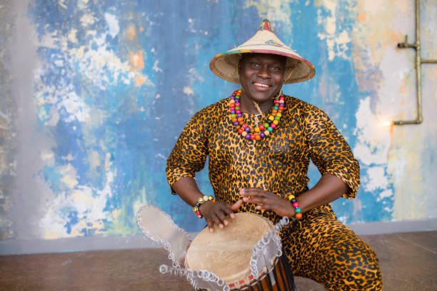 istock Handsome african drummer weared in traditional costume playing on djembe drum 1202847335