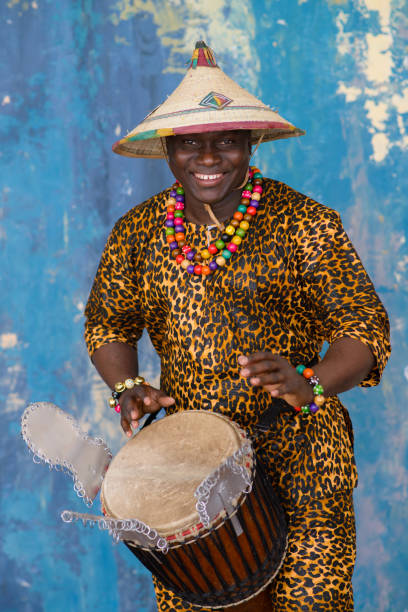 Handsome african drummer weared in traditional costume playing on djembe drum