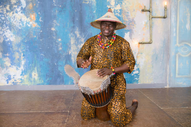 istock Handsome african drummer weared in traditional costume playing on djembe drum 1202847345