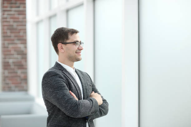 istock smiling business man looking through office window 1202857712