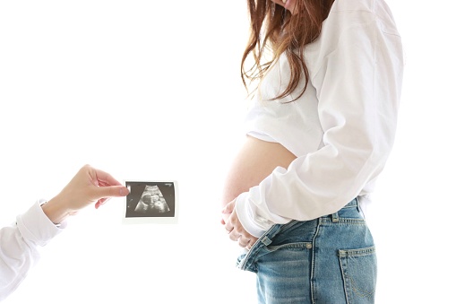 Close-up of Young Seven month Pregnant woman and ultrasound photo at hospital