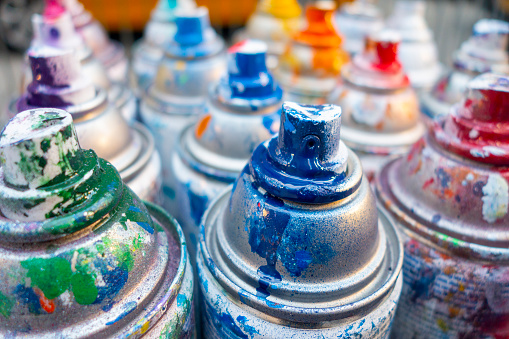 bunch of messy paint spray cans with colorful used paint markings