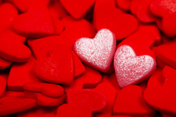 istock Two sweet hearts among many red hearts 1202875132