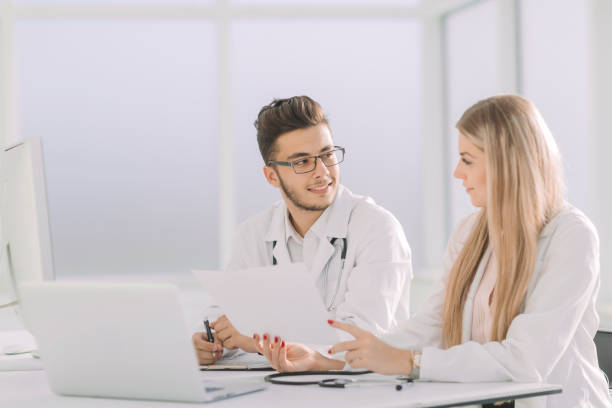 istock doctors colleagues talking sitting at a table in the office 1202877900