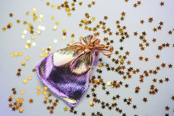 Golden little pouch or pouch on a background of luminous confetti or sparkle. Holiday concept.
