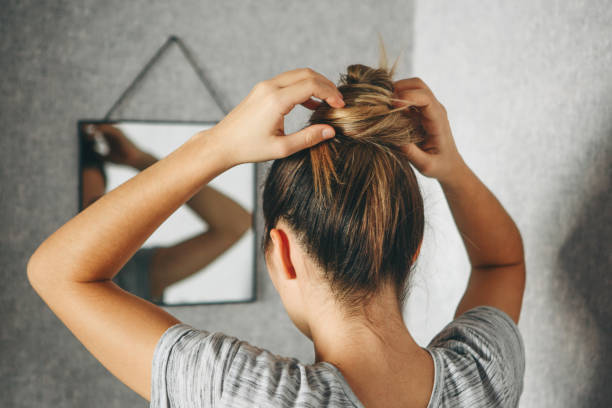 girl doing hairstyle at the mirror - woman in mirror backview imagens e fotografias de stock