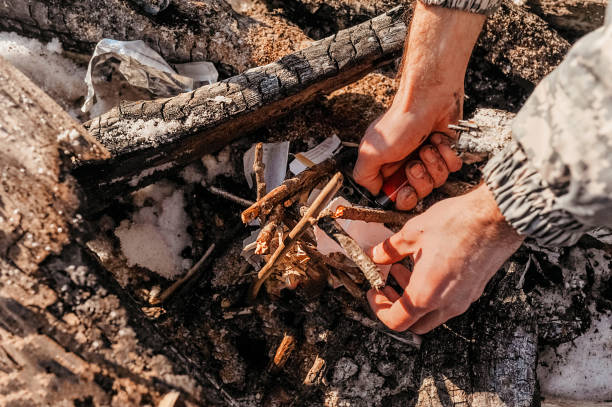 istock lighter in rough hands set fire to paper and logs to make a fire for camping 1202885734
