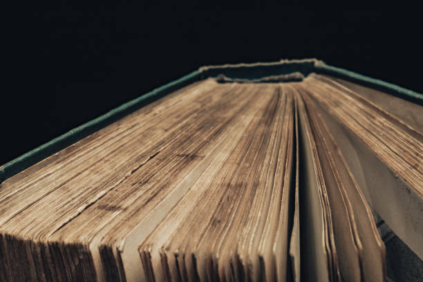 istock Close up ancient book shot on black background. The book is in bad condition. 1202889155