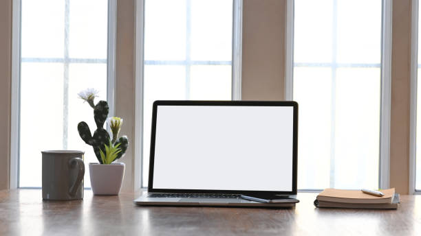 istock Blank screen laptop putting on the wooden working desk including cactus, coffee cup, notebook and smartphone. Modern working desk concept. 1202890168