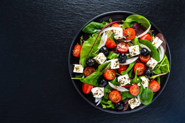 istock Greek salad on black stone background 1202890544
