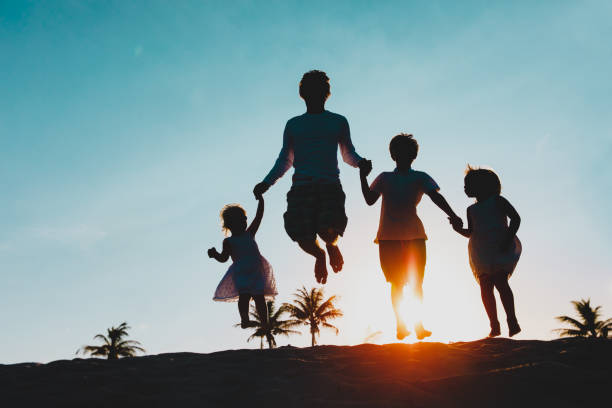 istock happy father with kids jumping from joy at sunset 1202891794