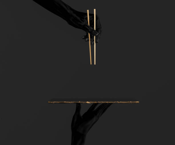 Black hands using gold chopsticks and sushi dish isolated on black