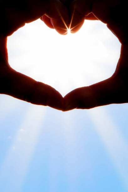 istock Hands forming a heart shape over the sun 1202895657