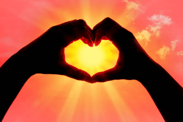 istock Hands forming a heart shape over the sun 1202895721