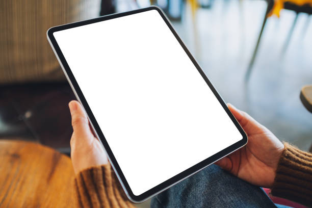 une femme retenant le pc noir de tablette avec l'écran blanc blanc sur la table en bois - tablet pc photos et images de collection