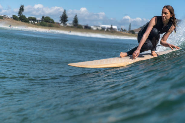 Surfer girl riding the wave A young surfer woman sliding on a longboard, Mount Maunganui, New Zealand mount maunganui stock pictures, royalty-free photos & images