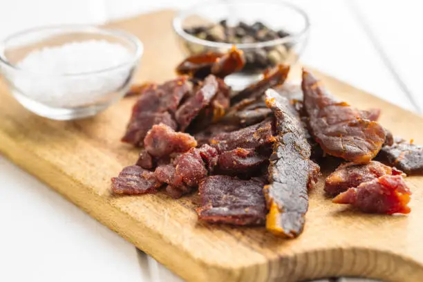 Beef jerky pieces. Dried beef meat on cutting board.
