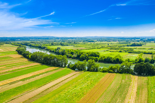 Rural countryside landscape in Croatia, Kupa river meandering between agriculture fields, shot from drone