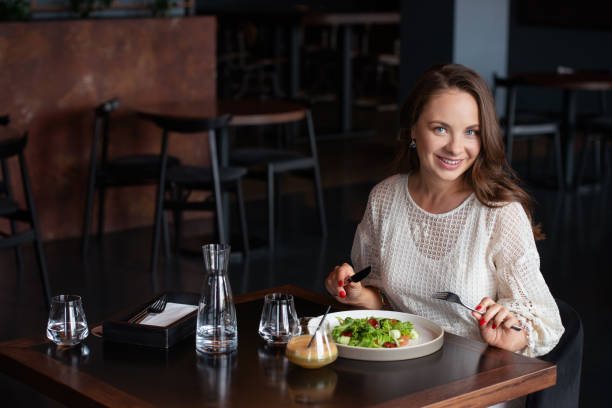 istock Smiling woman eats vegetarian salad in cafe 1202903274