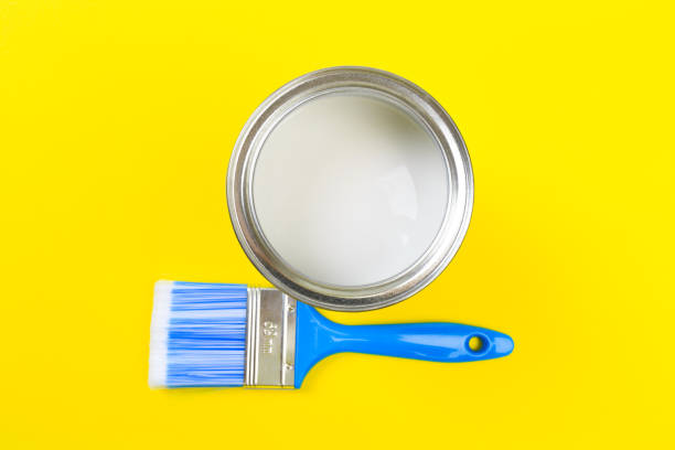istock White Paint Can with Brush Top View On Yellow Background. 1202903380