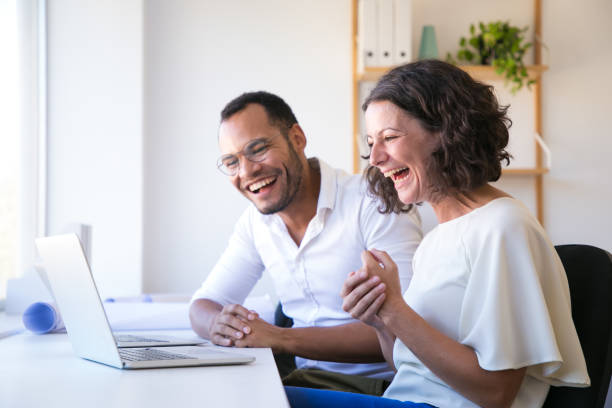 cheerful employees looking at laptop and laughing - group of objects business human resources laptop imagens e fotografias de stock