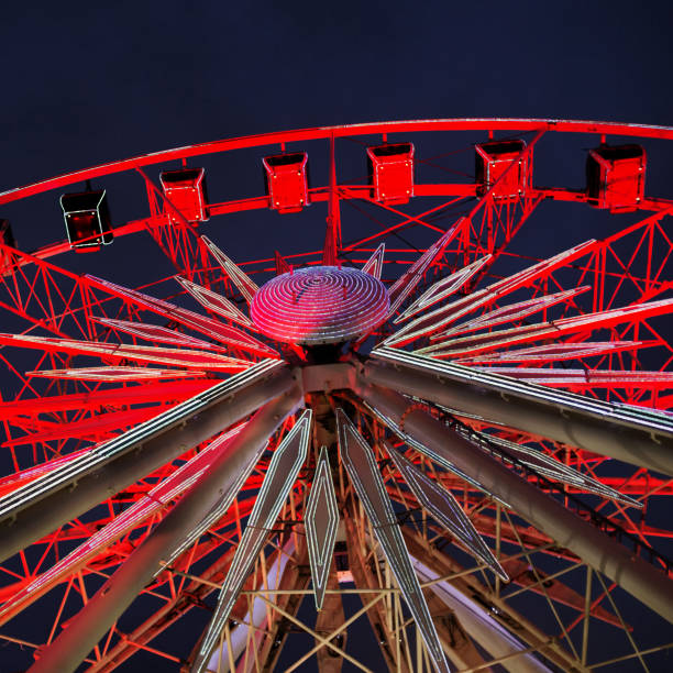 istock Looking up at red Ferris wheel turning in darkness 1202906677