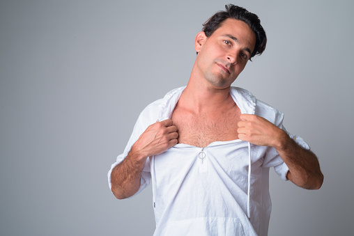 Studio shot of handsome Hispanic man wearing hooded shirt against white background