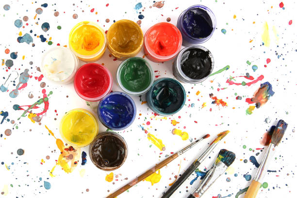 istock Jars with gouache paints and brushes on colorful paint splashes background. 1202907289