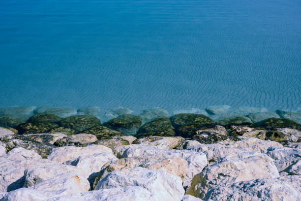 Rocks on the seashore with clear water waves on blue sea background, Bahrain