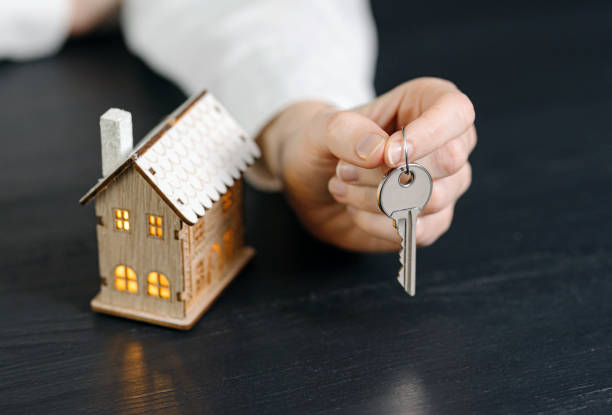 istock small house with luminous windows in female hands 1202910225