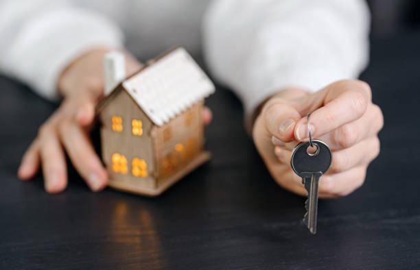 istock small house with luminous windows in female hands 1202910331