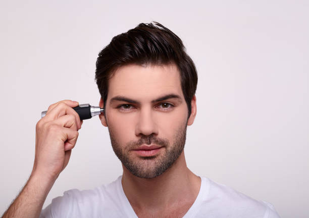 istock Close-up is a handsome guy with a trimmer in his ech. 1202910395