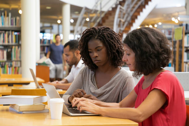 istock Two thoughtful women talking and typing on laptop 1202910571