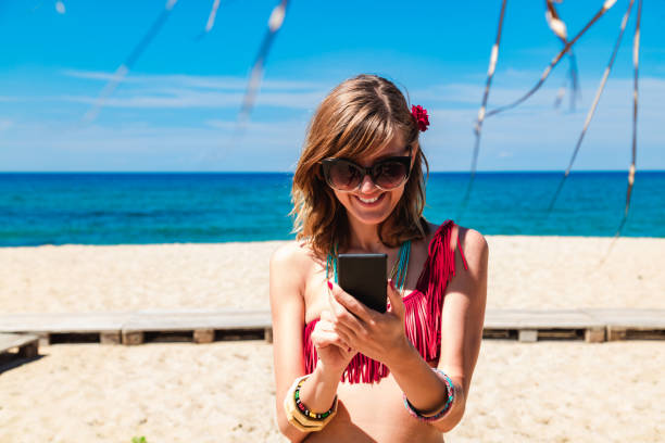 istock Young woman using cellphone on a tropical sandy beach. 1202911140